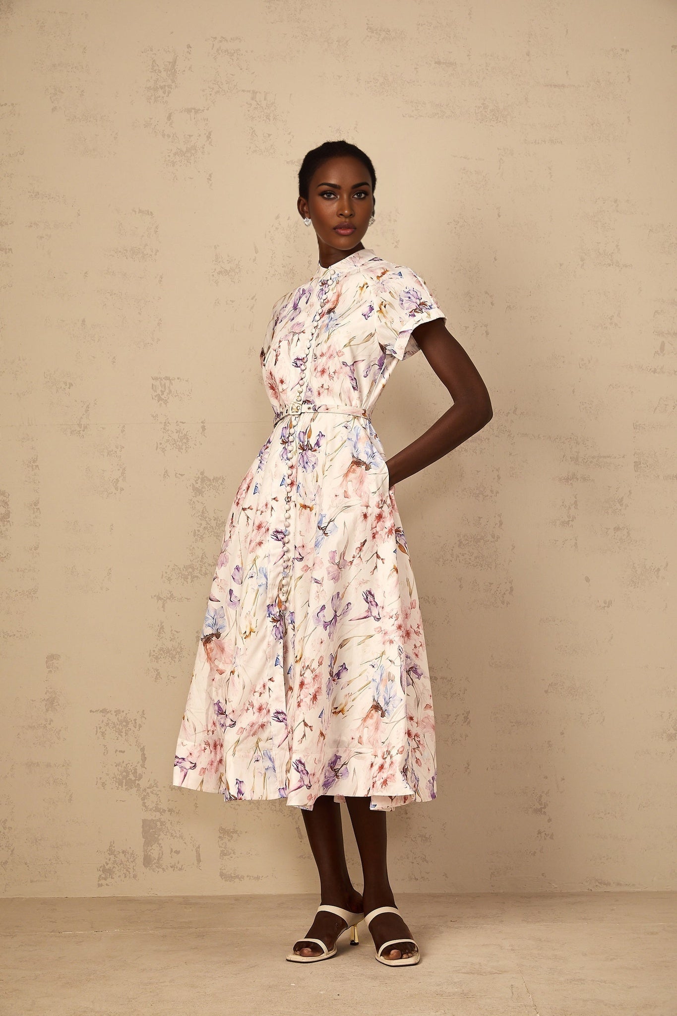 A white midi dress with a floral print and mock neckline worn by a woman named Geraldine