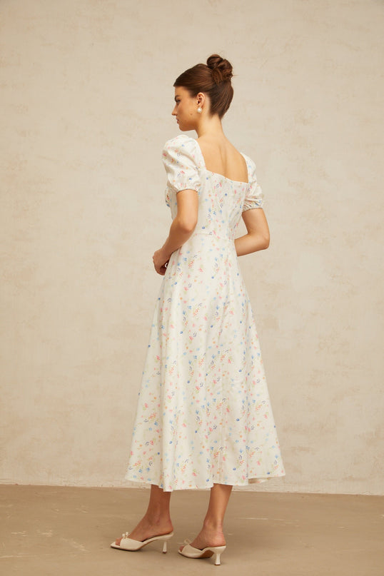 A white midi dress with a floral print pattern and flared skirt design worn by a female model