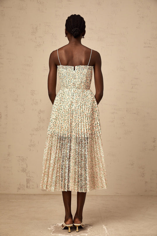 A white midi dress with a floral print pattern and pleated design featuring a flowing silhouette and delicate details