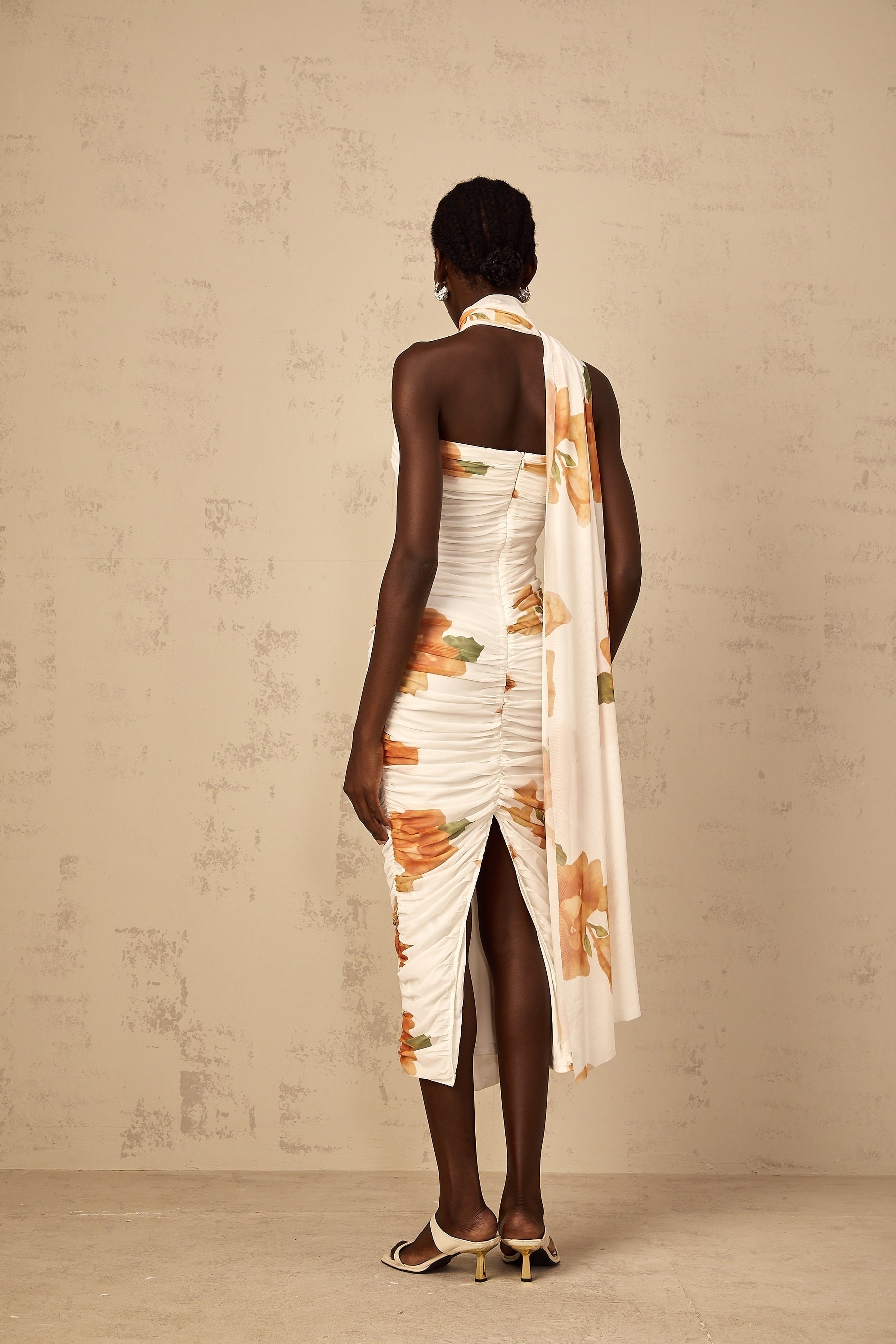 A white midi dress with a floral print pattern made of ruched tulle fabric featuring a feminine and romantic design