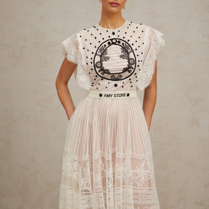 A white midi dress with a jacquard floral lace pattern featuring pleats and a delicate Phoebe design