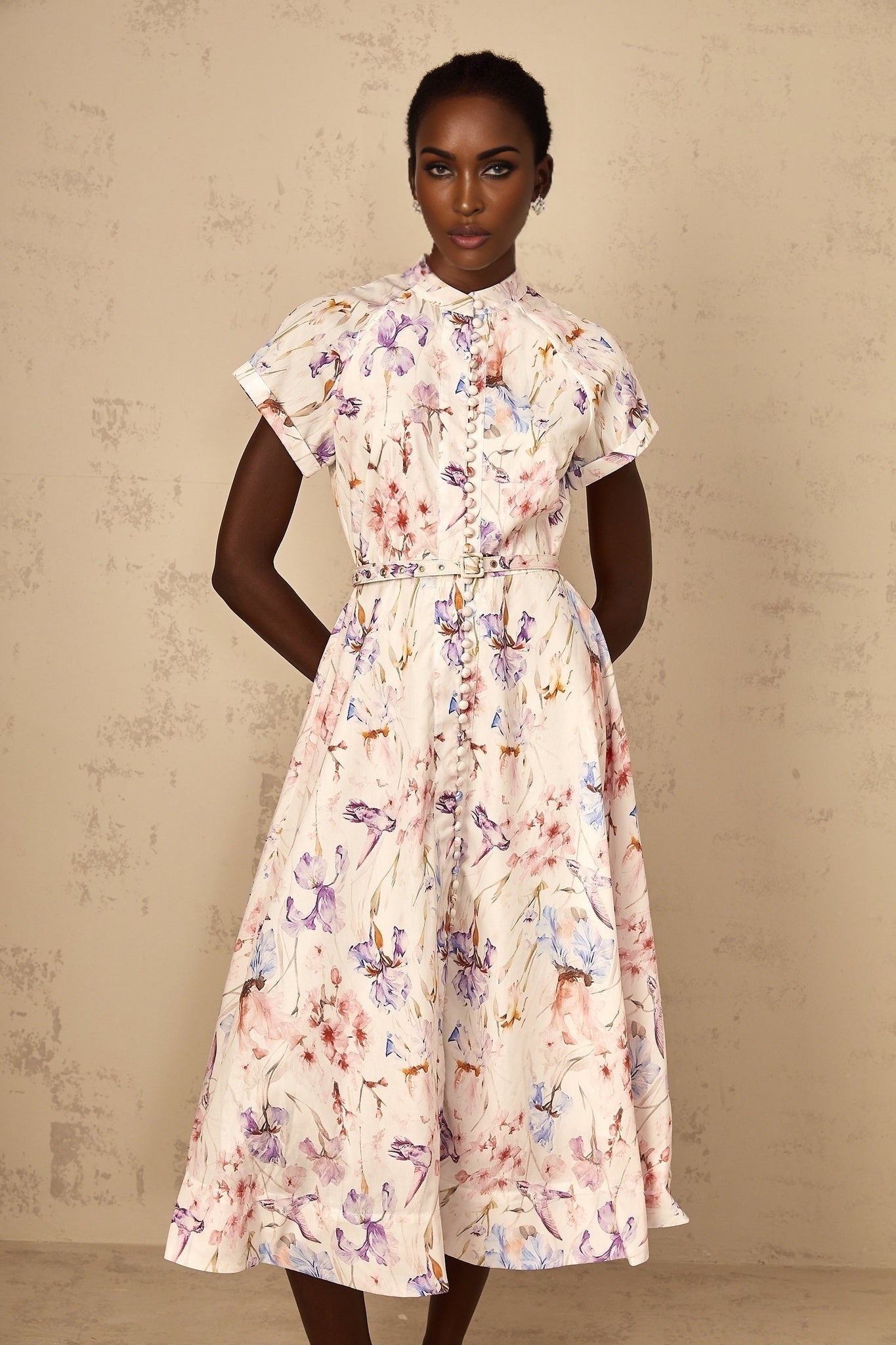 A white midi dress with a mock neck and floral print worn by a woman named Geraldine