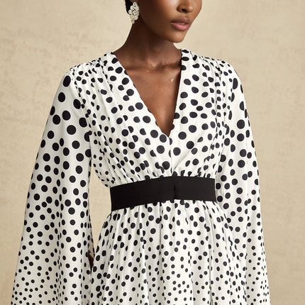 A white midi dress with black polka dots featuring slit sleeves and a feminine silhouette