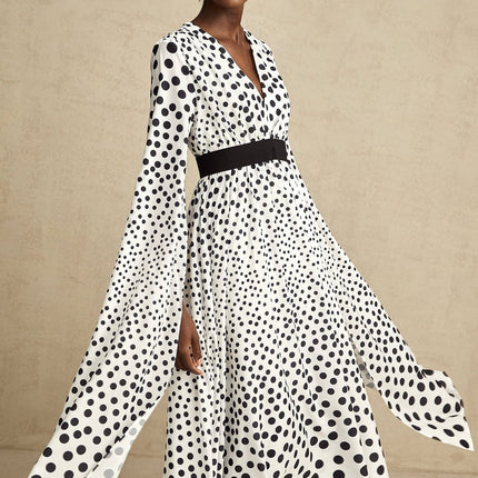 A white midi dress with black polka dots featuring slit sleeves and a fitted silhouette on a female model
