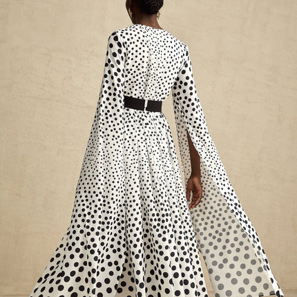 A white midi dress with black polka dots featuring slit sleeves and a fitted silhouette