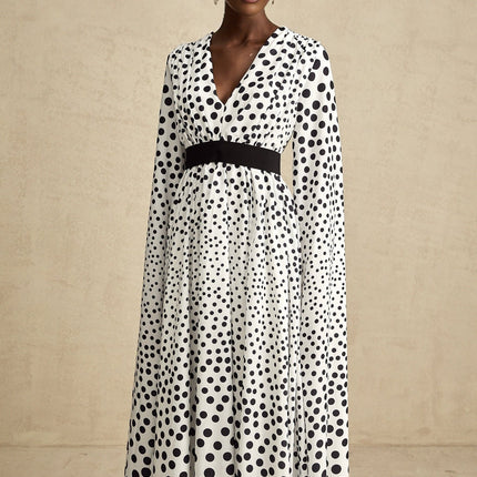 A white midi dress with black polka dots featuring slit sleeves and a fitted silhouette