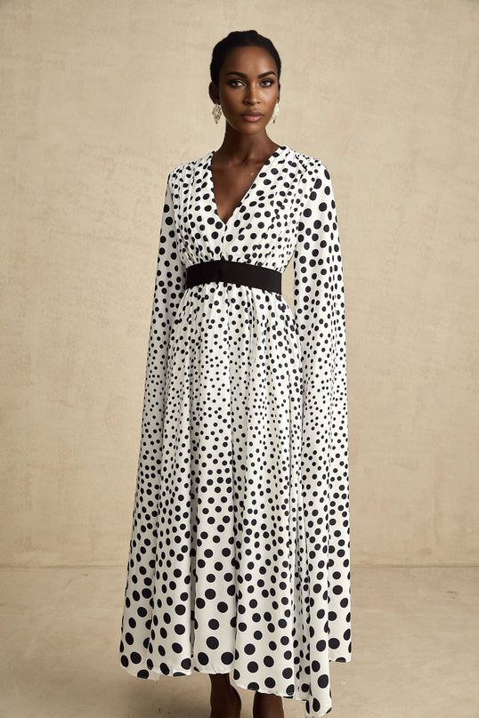 A white midi dress with black polka dots featuring slit sleeves and a fitted silhouette