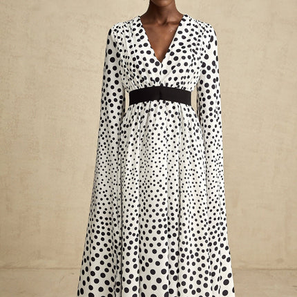 A white midi dress with black polka dots featuring slit sleeves and a fitted silhouette