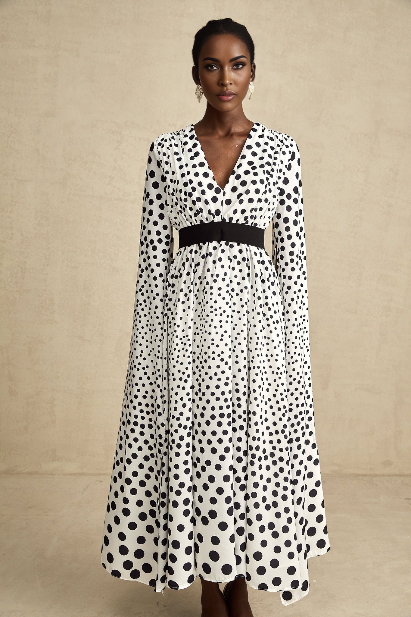 A white midi dress with black polka dots featuring slit sleeves and a fitted silhouette