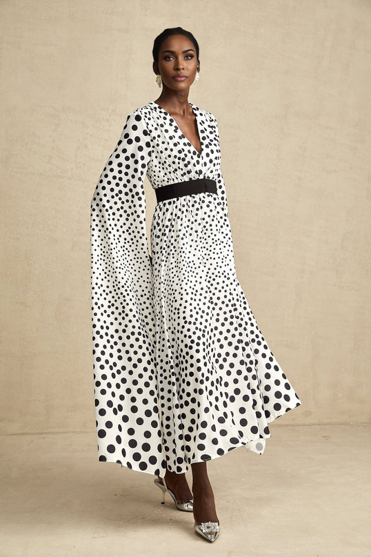A white midi dress with black polka dots featuring slit sleeves and a fitted silhouette