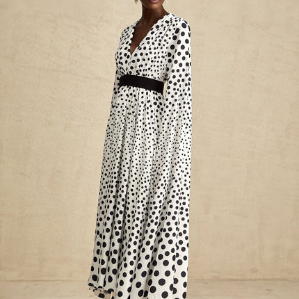 A white midi dress with black polka dots featuring slit sleeves and a fitted silhouette