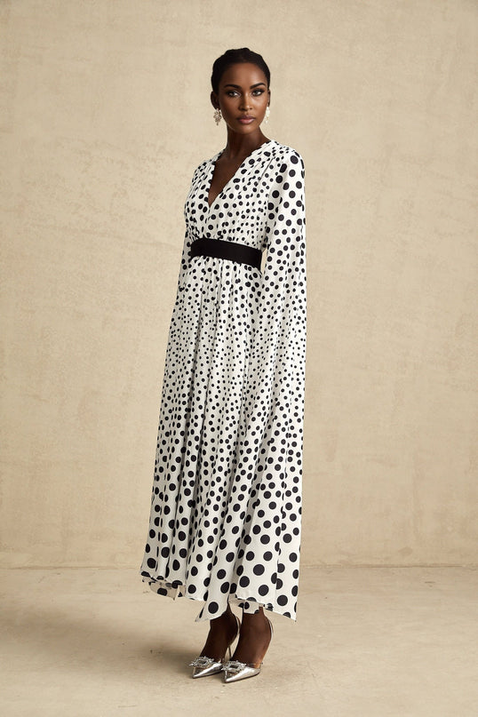 A white midi dress with black polka dots featuring slit sleeves and a fitted silhouette
