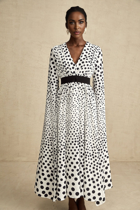 A white midi dress with black polka dots featuring slit sleeves and a fitted silhouette