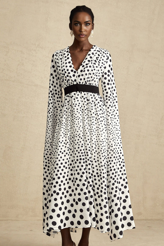 A white midi dress with black polka dots featuring slit sleeves and a fitted silhouette