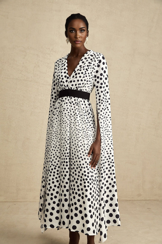 A white midi dress with black polka dots featuring slit sleeves and a fitted silhouette