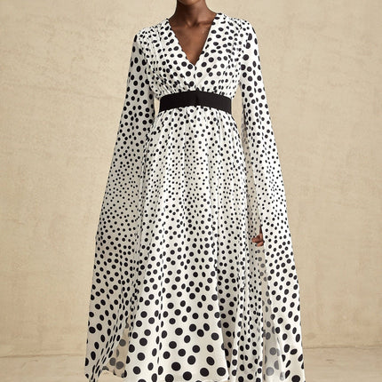A white midi dress with black polka dots featuring slit sleeves and a fitted silhouette