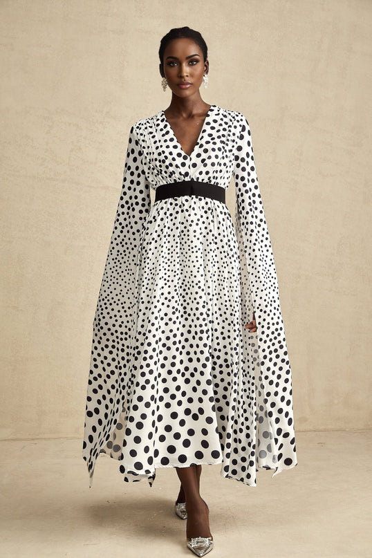 A white midi dress with black polka dots featuring slit sleeves and a fitted silhouette