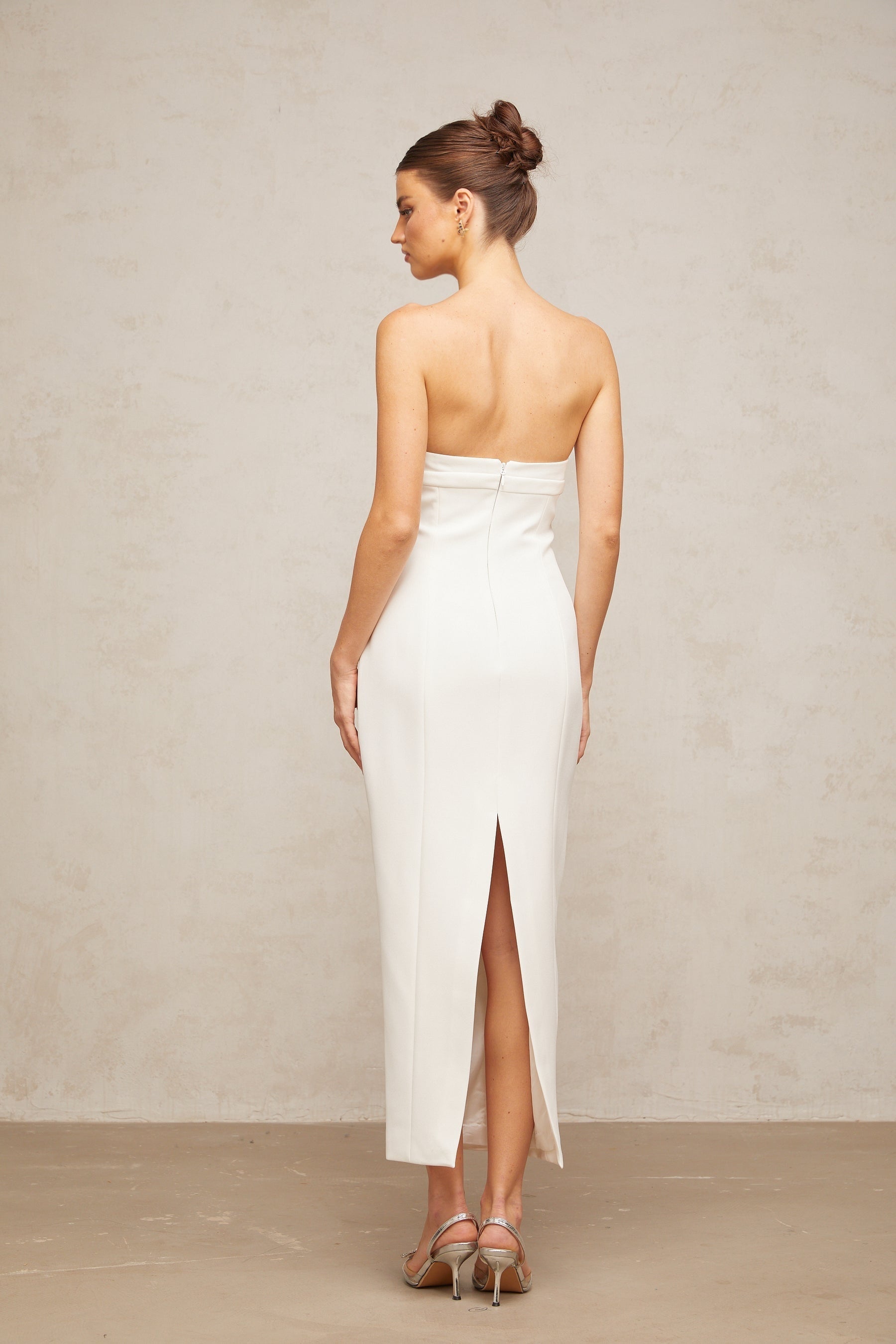 A white midi dress with corset styling and bow details named Isaline