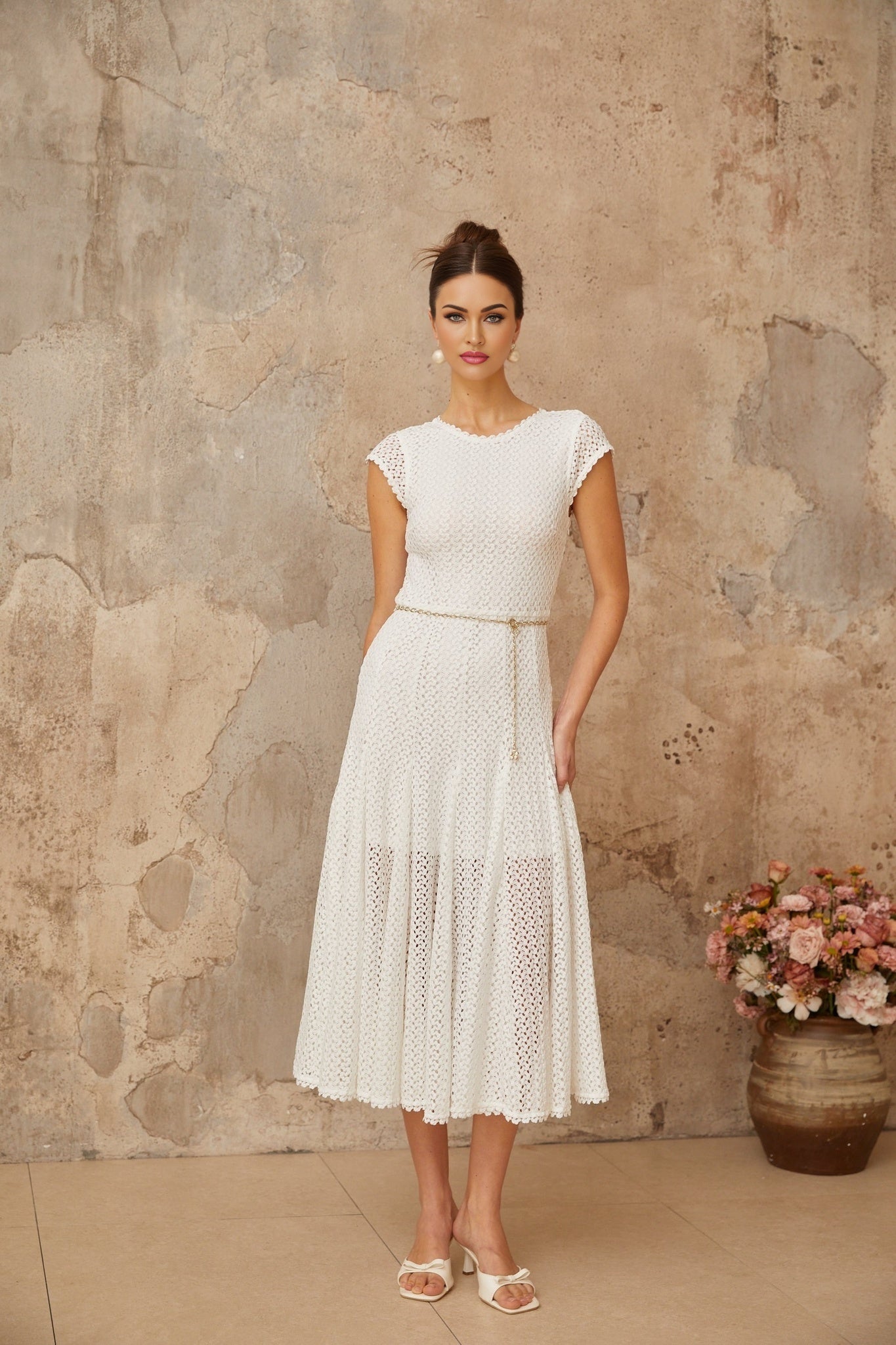 A white midi dress with crochet knit detailing and shirred fabric featuring a fitted bodice and flowy skirt