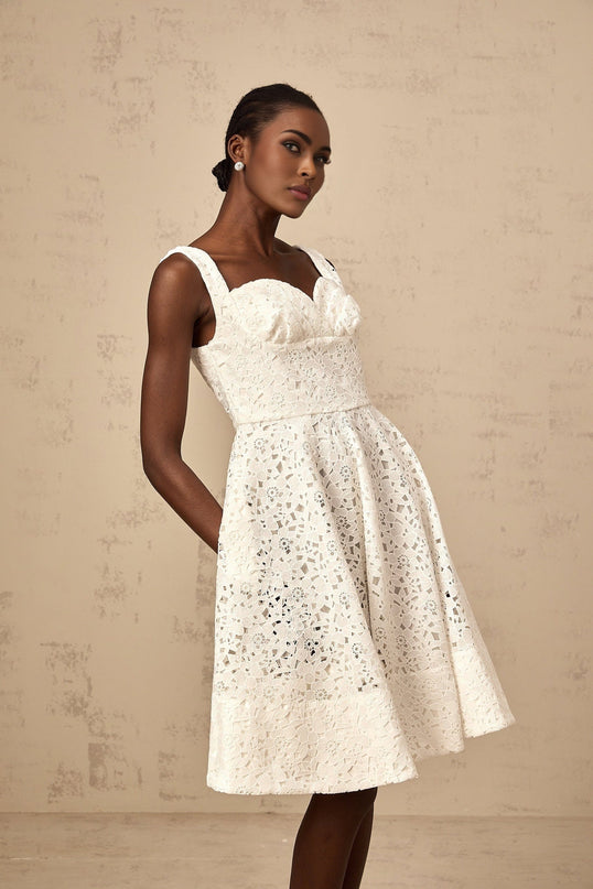 A white midi dress with delicate floral lace pattern featuring a feminine silhouette and romantic design details
