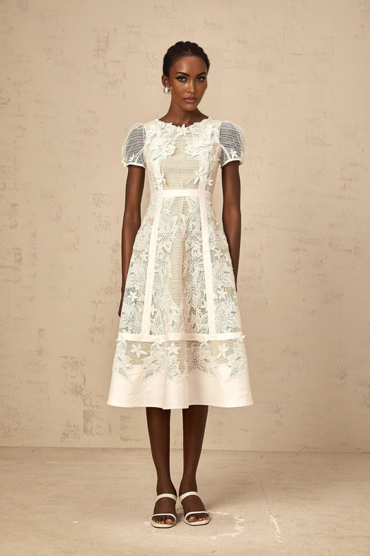 A white midi dress with delicate flower embroidery featuring a feminine silhouette and intricate floral details