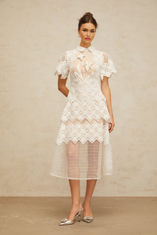 A white midi dress with floral embroidery called Yasmine featuring a fitted bodice and flowing skirt