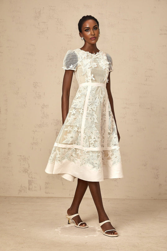 A white midi dress with floral embroidery featuring a feminine silhouette and delicate flower patterns adorning the fabric