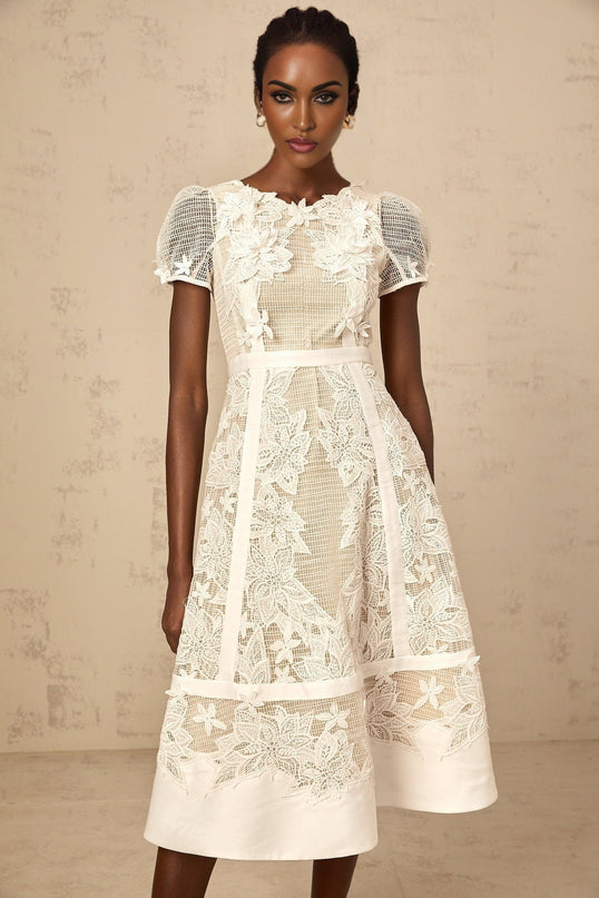 A white midi dress with floral embroidery featuring a feminine silhouette and delicate flower patterns