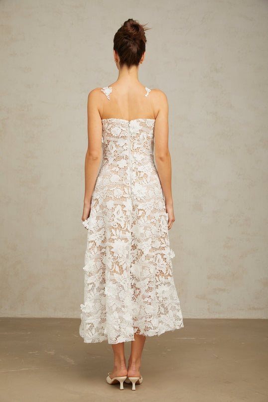 A white midi dress with lace and tulle panels featuring a delicate floral pattern and a feminine silhouette