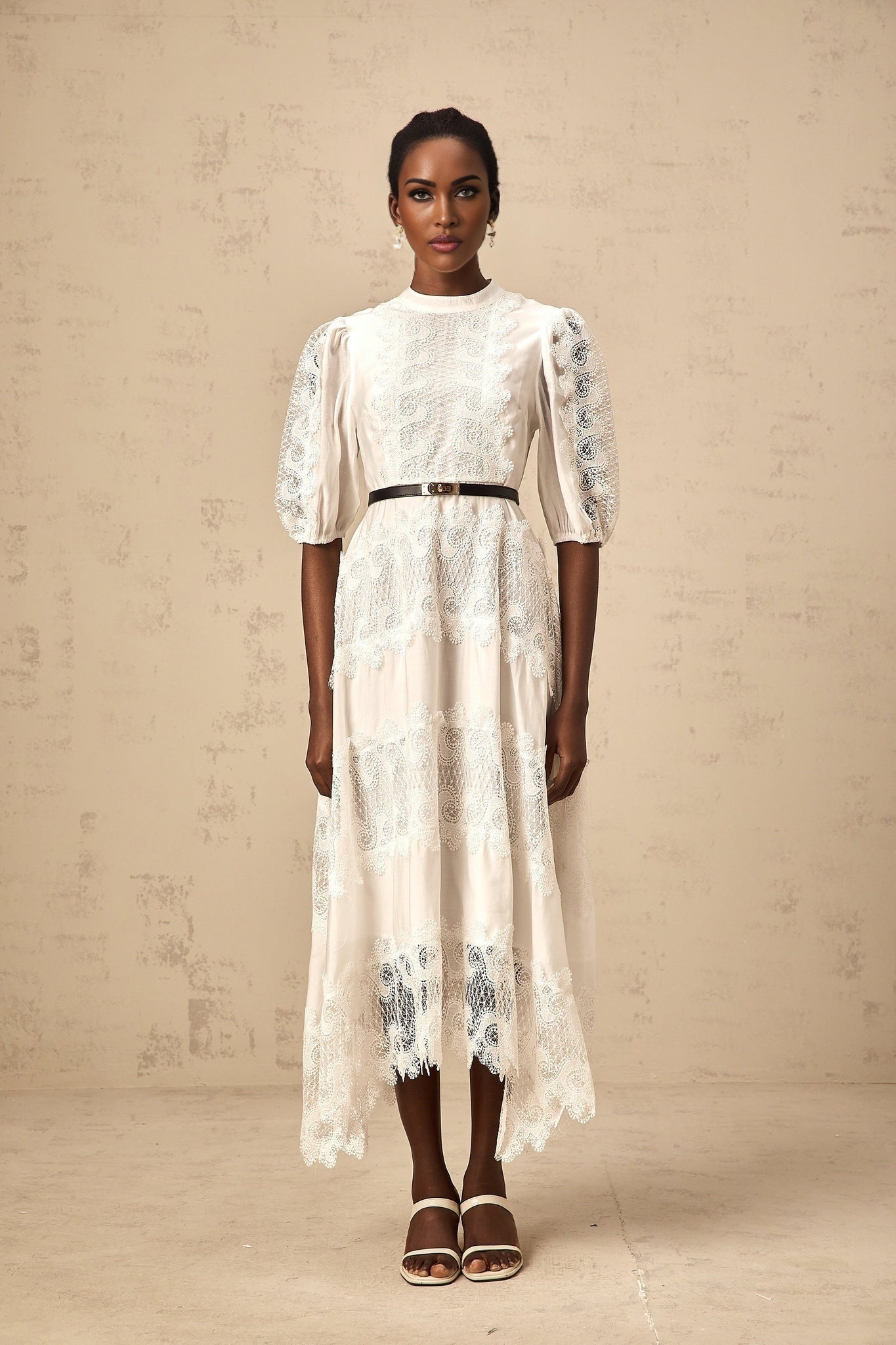 A white midi dress with lace trim panels and a belt at the waist featuring a sleeveless design and a flowy skirt