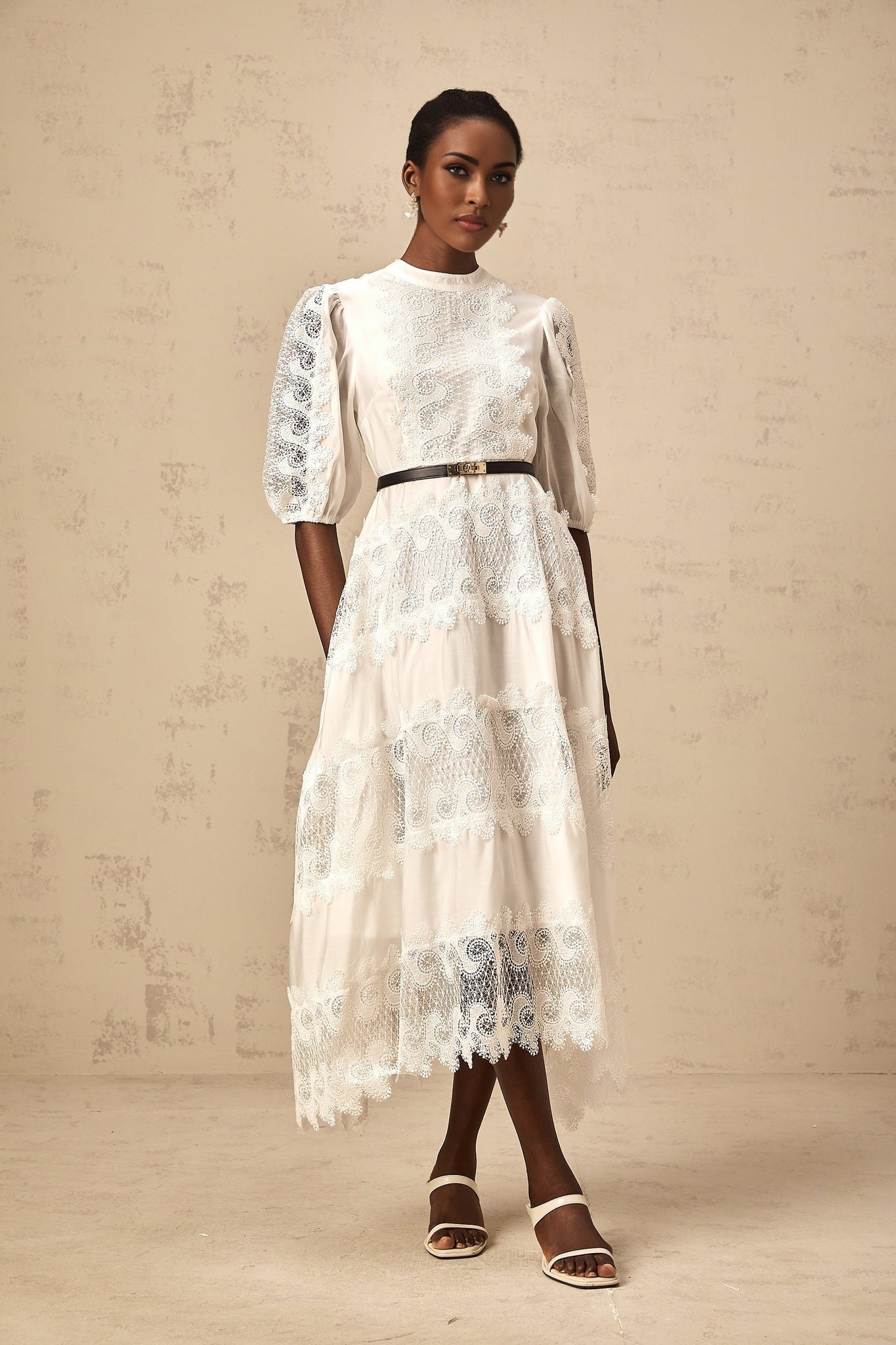 A white midi dress with lace trim panels and a belt at the waist