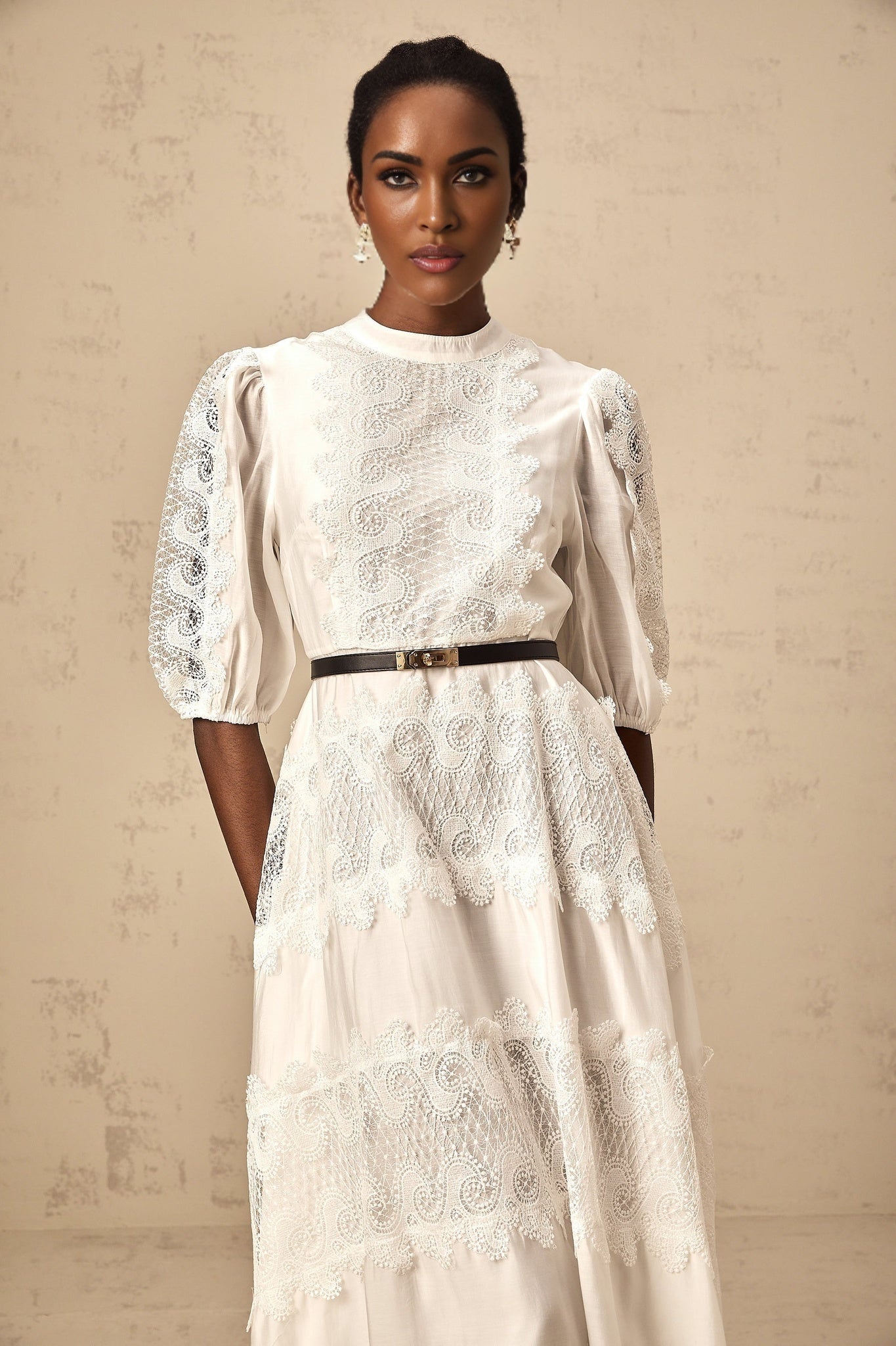 A white midi dress with lace trim panels and a belt at the waist