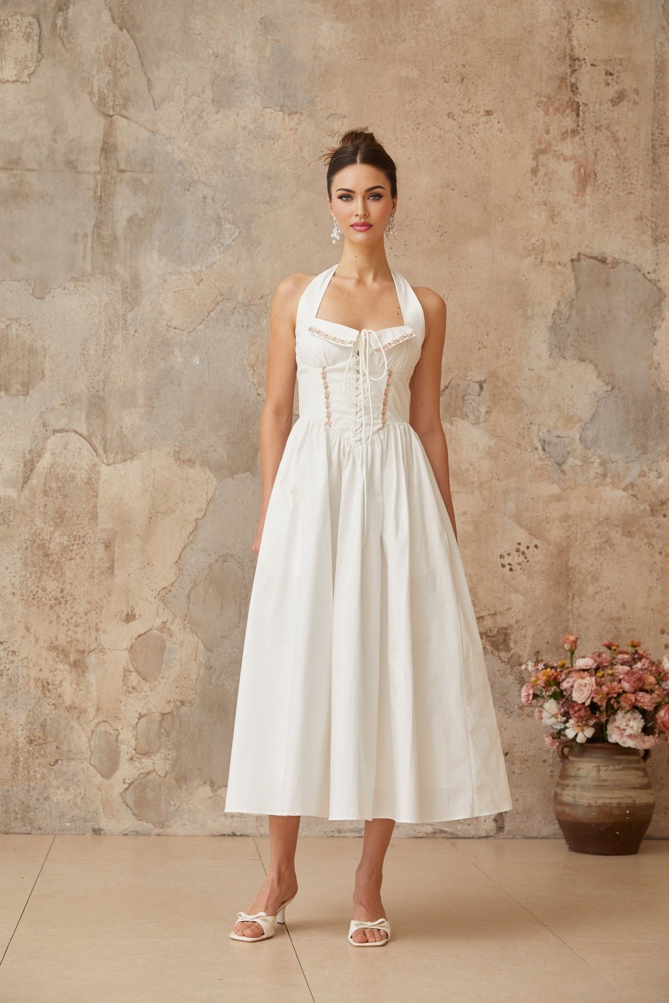A white midi dress with laceup detailing and shirred fabric featuring a fitted bodice and flowy skirt