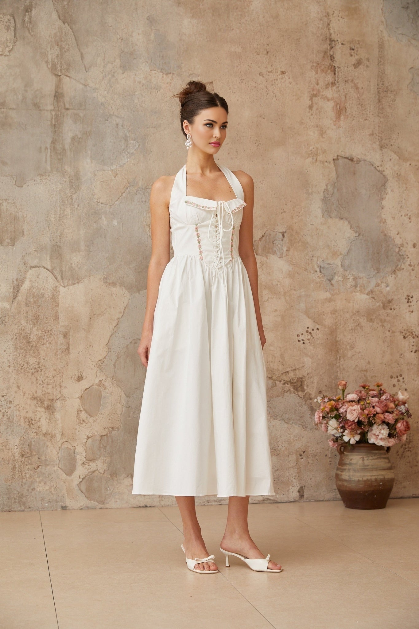 A white midi dress with laceup details and shirred fabric featuring a fitted bodice and flowy skirt