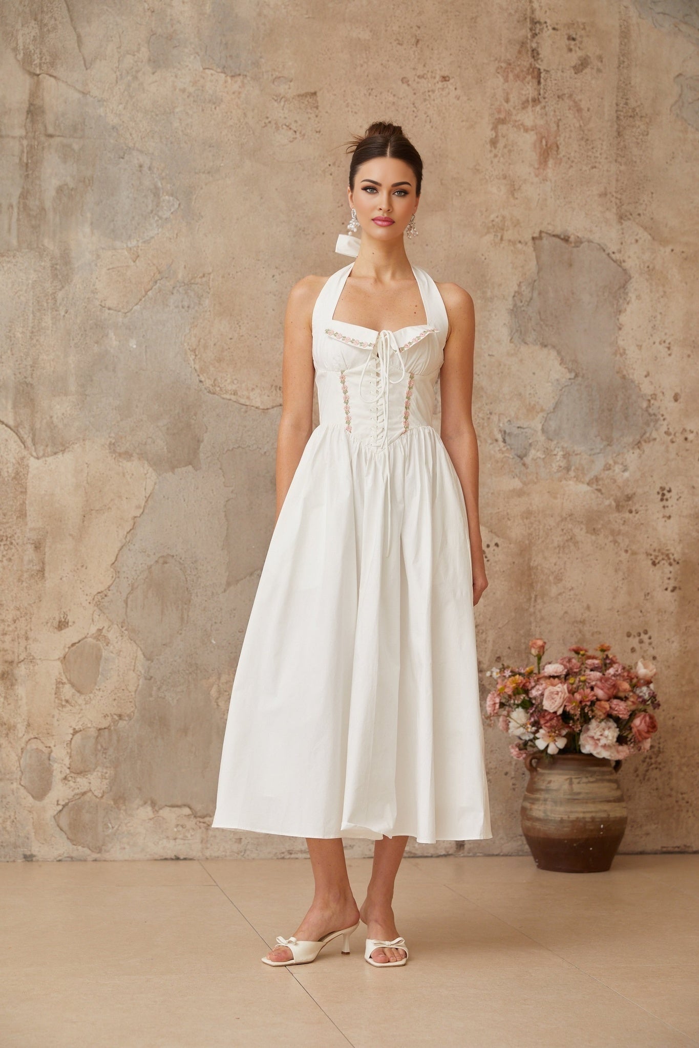 A white midi dress with laceup details and shirred fabric featuring a fitted bodice and flowy skirt
