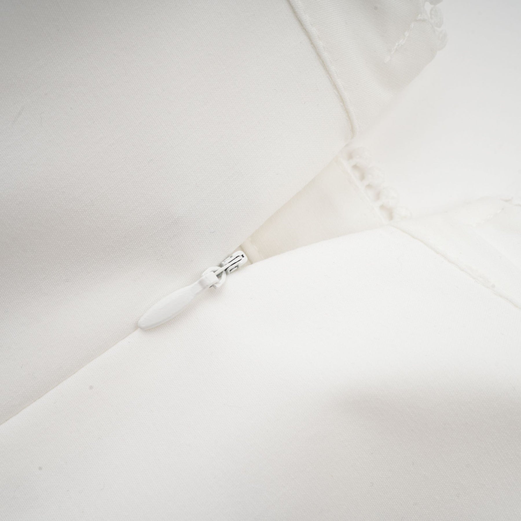 A white midi dress with panelled design and embroidery details named Madeleine featuring a flowy silhouette and delicate stitching patterns