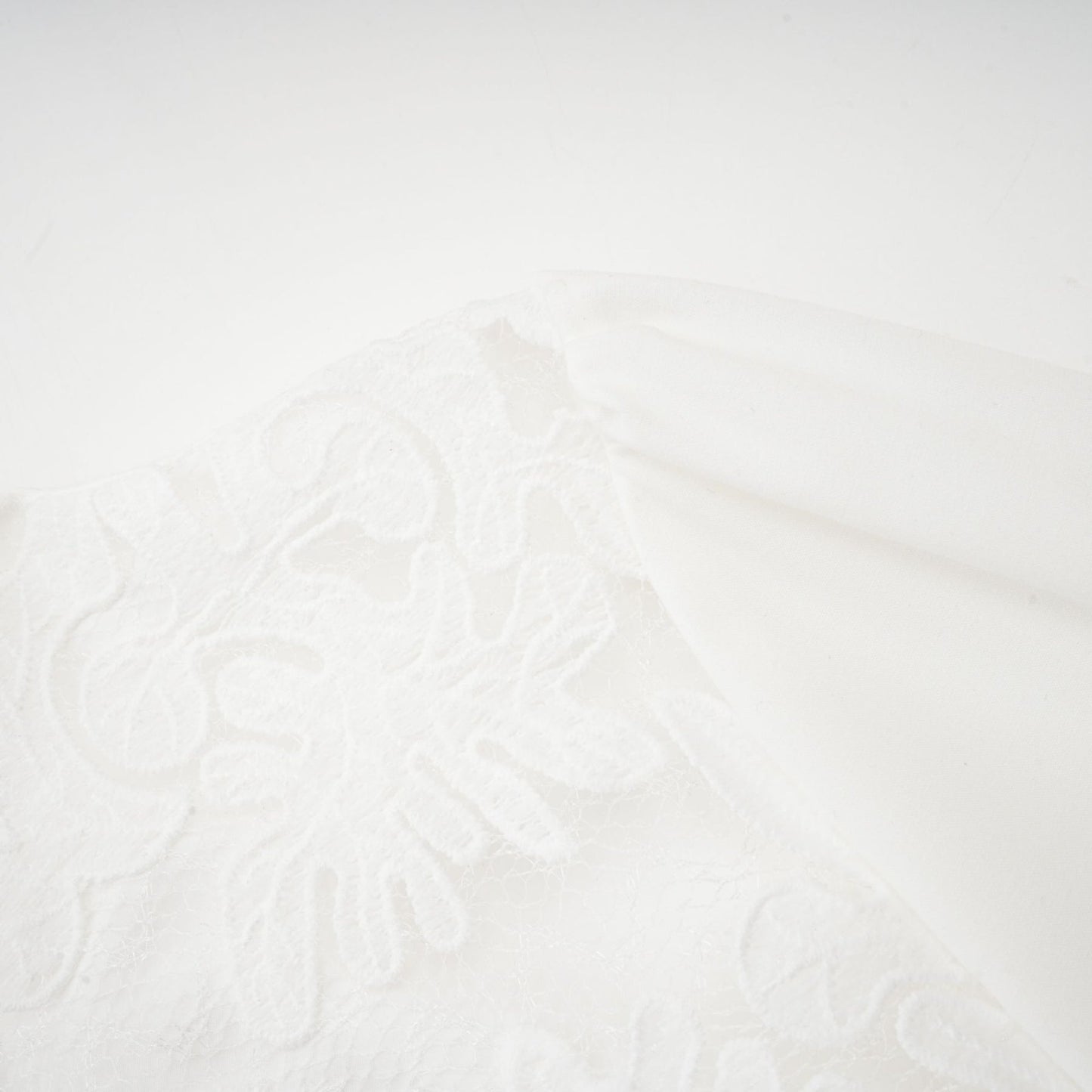 A white midi dress with panelled design and embroidery details named Madeleine featuring a flowy silhouette and delicate stitching throughout