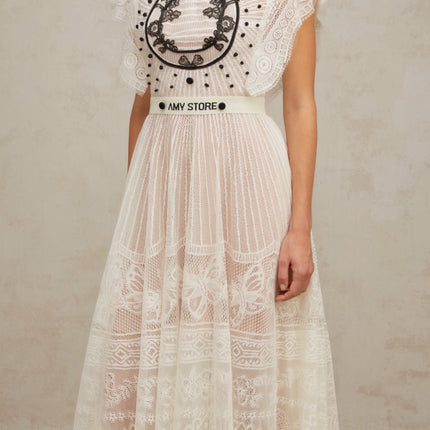 A white midi dress with pleated skirt featuring jacquard floral lace pattern named Phoebe