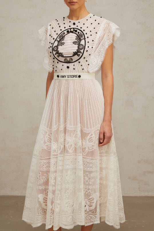 A white midi dress with pleated skirt featuring jacquard floral lace pattern named Phoebe