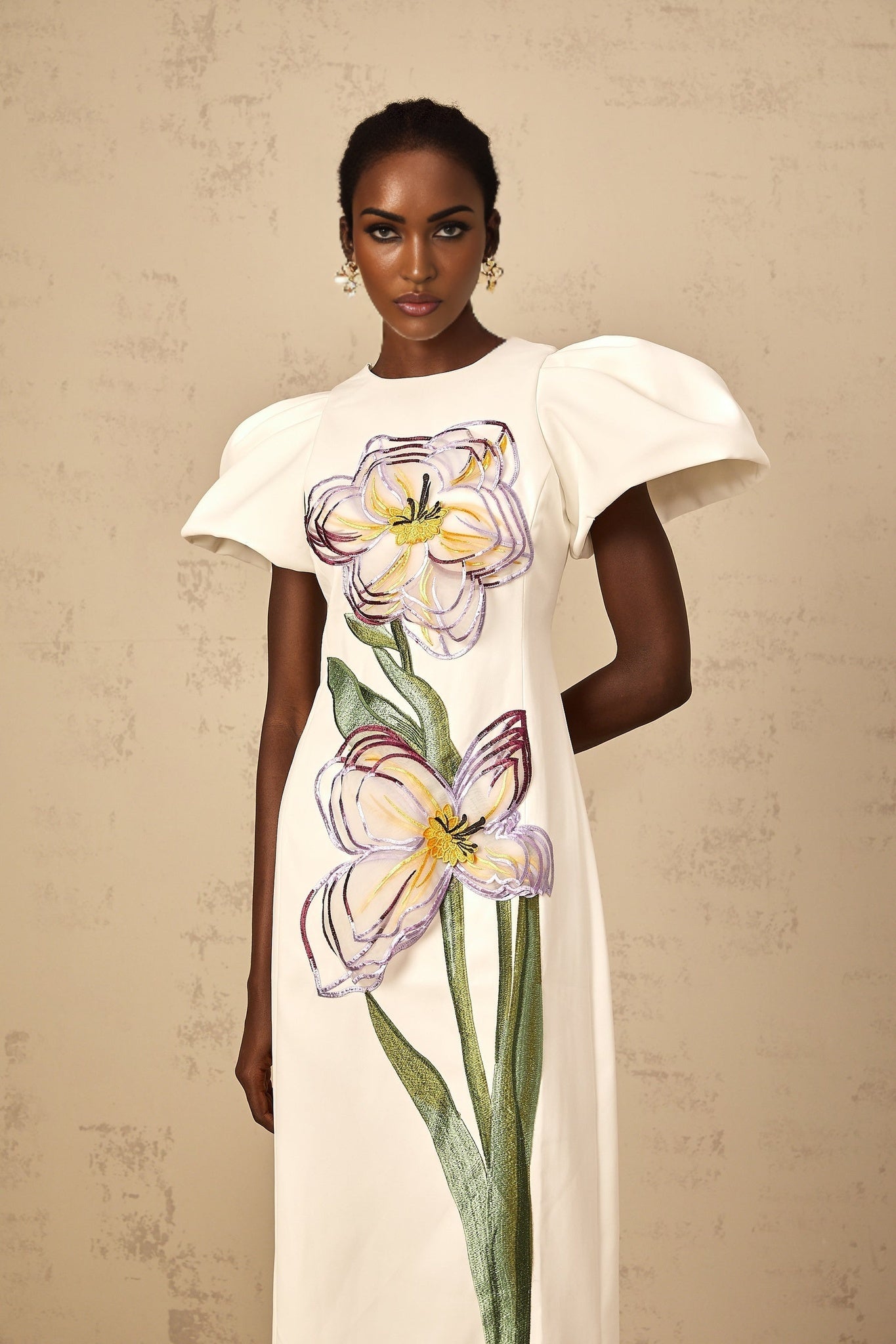 A white midi dress with sequin floral embroidery on display featuring delicate floral patterns and a shimmering effect created by the sequins