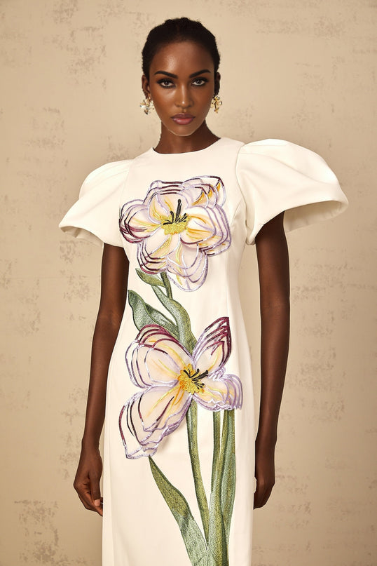 A white midi dress with sequin floral embroidery worn by a woman named Irene