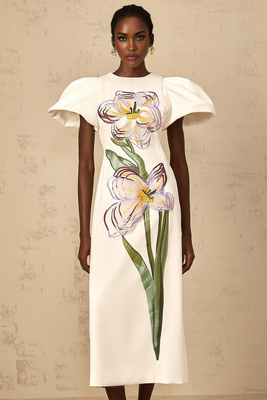 A white midi dress with sequin floral embroidery worn by a woman standing against a plain background