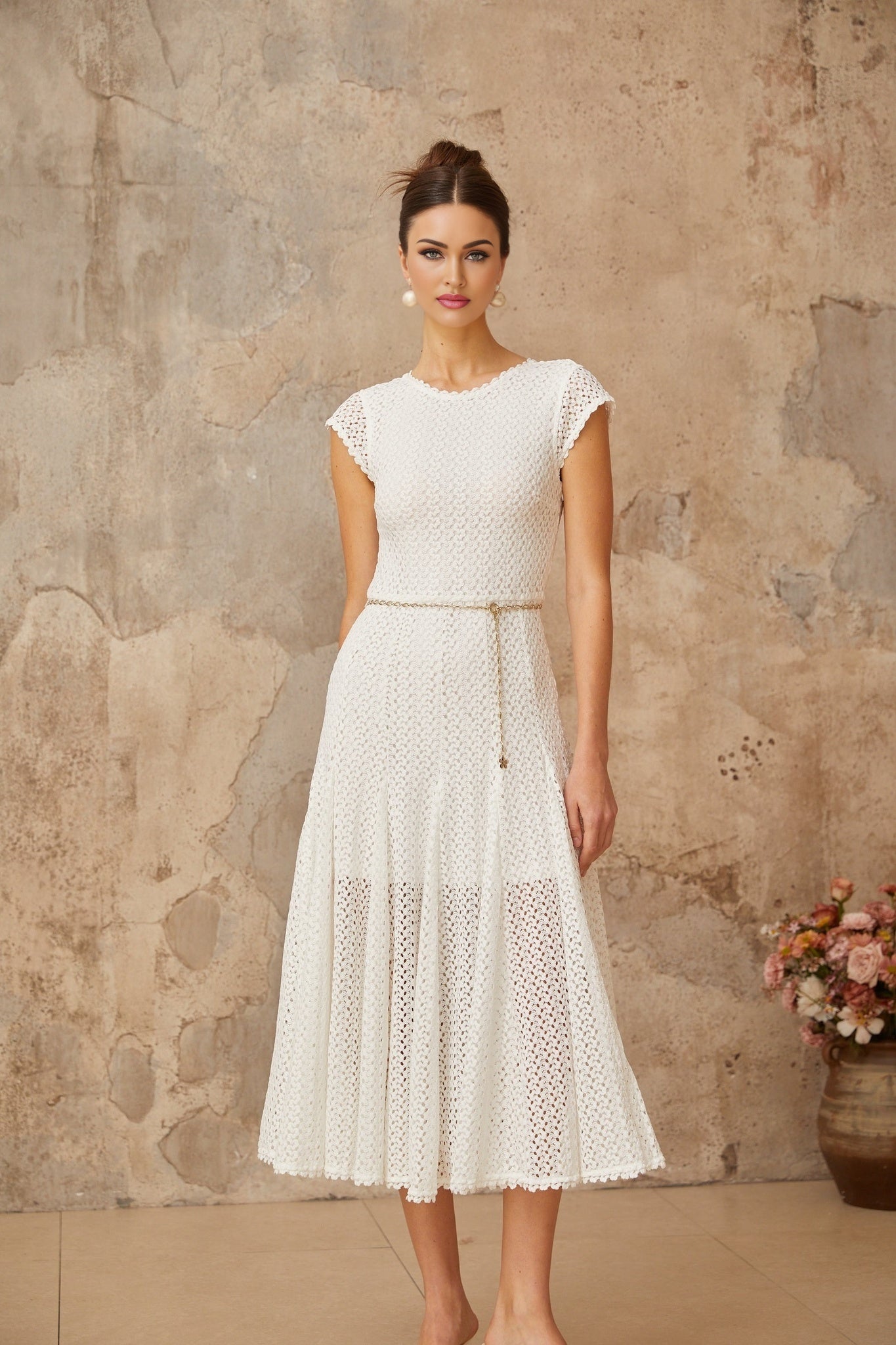A white midi dress with shirred and crochet knit details featuring a fitted bodice and flowy skirt