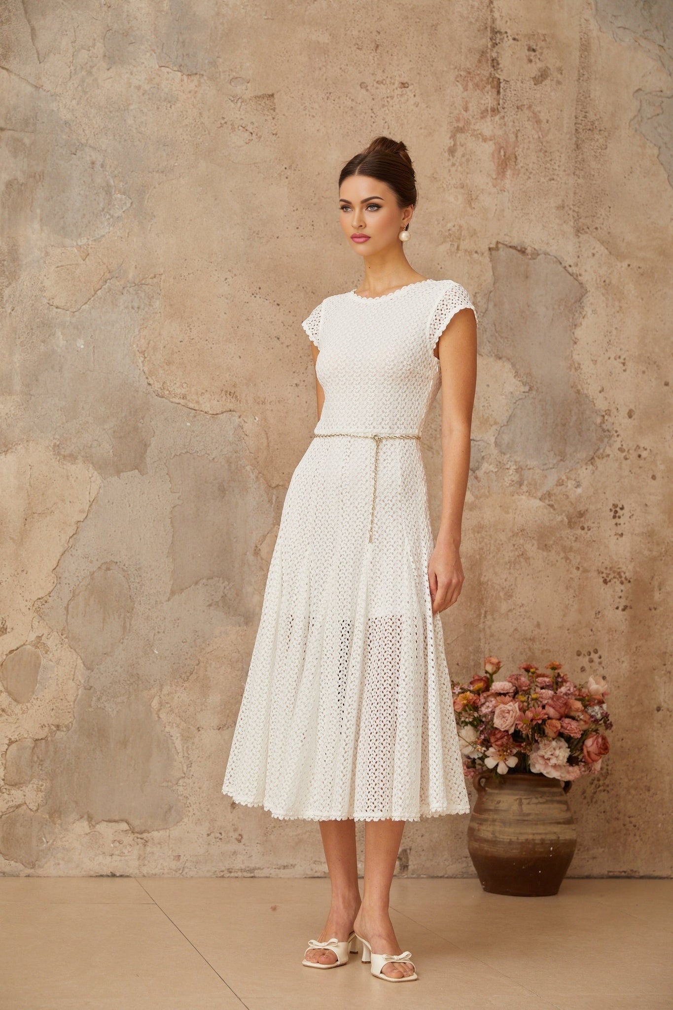 A white midi dress with shirred bodice and crochet knit details featuring a slim fit and sleeveless design