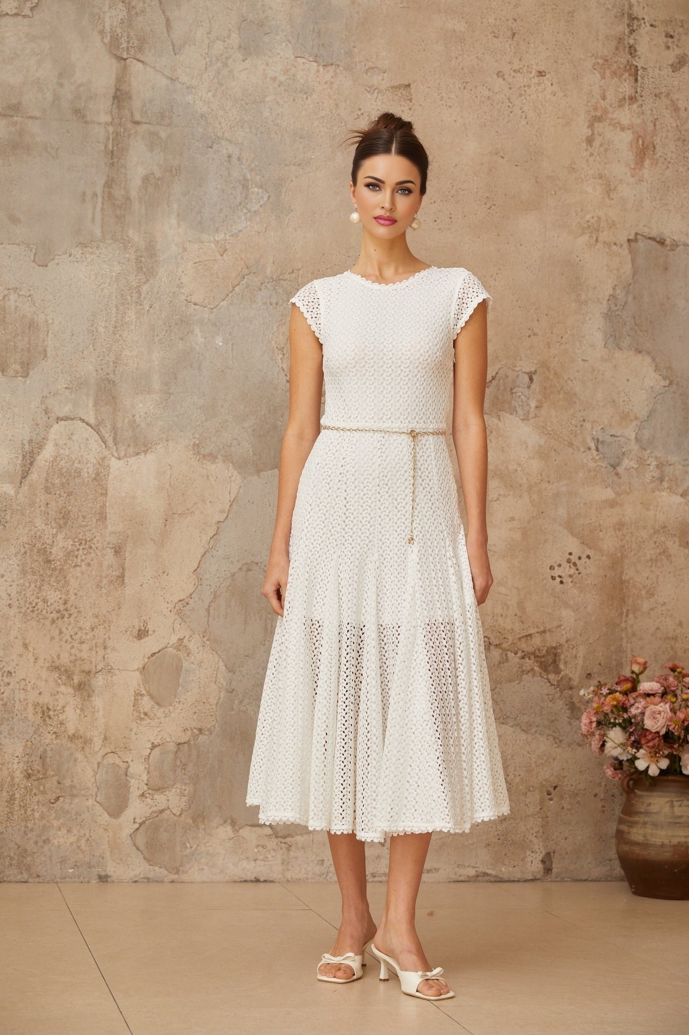 A white midi dress with shirred detailing and crochet knit fabric featuring a fitted bodice and flowing skirt