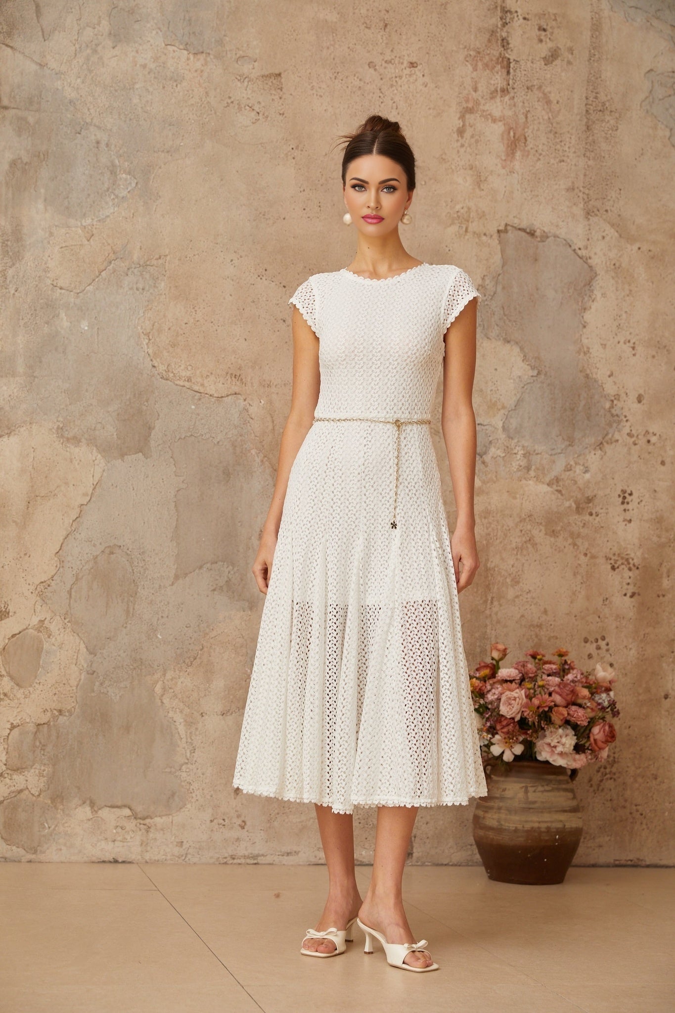 A white midi dress with shirred detailing and crochet knit fabric featuring a fitted bodice and flowy skirt on a female model