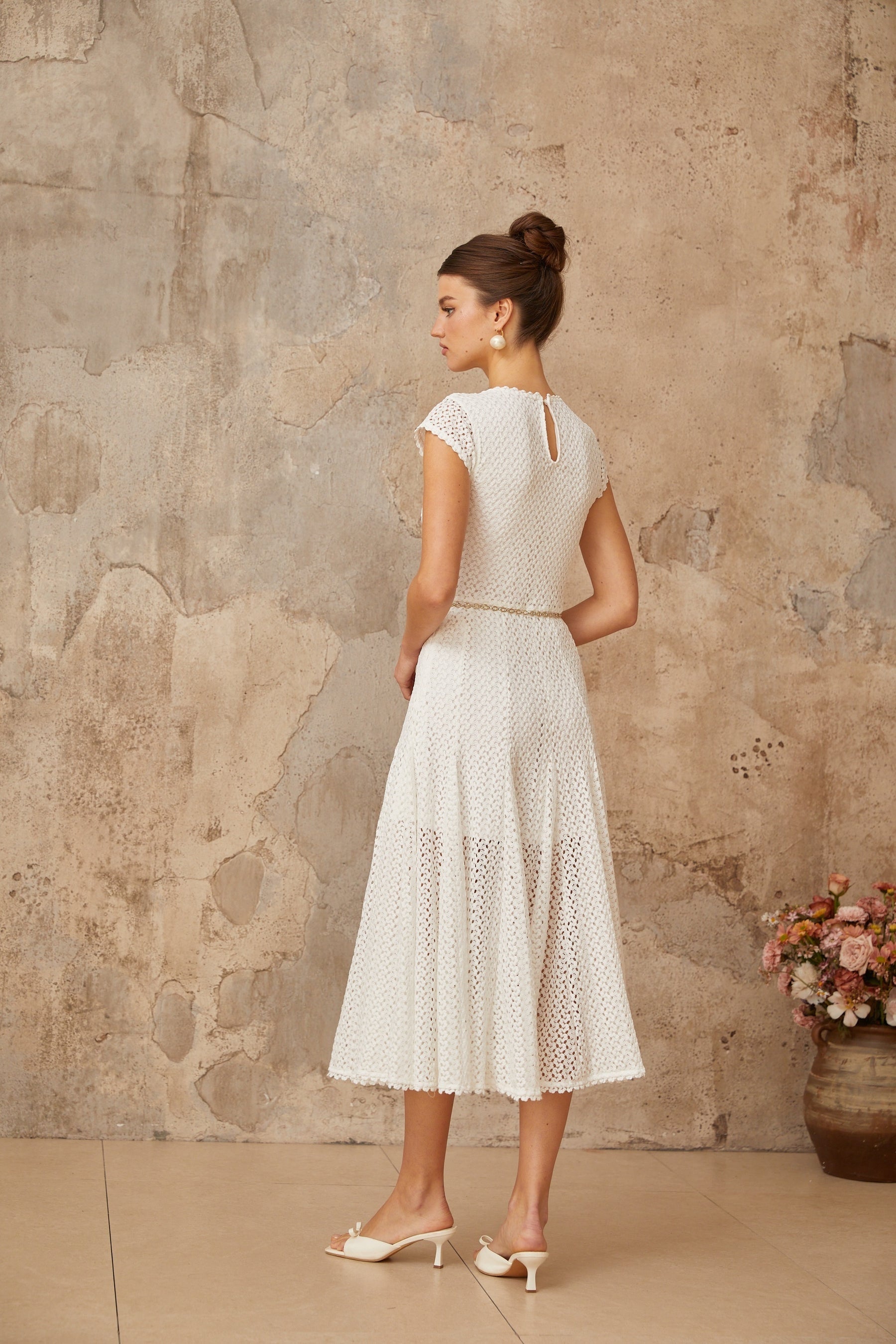 A white midi dress with shirred detailing and crochet knit pattern featuring a fitted bodice and flared skirt