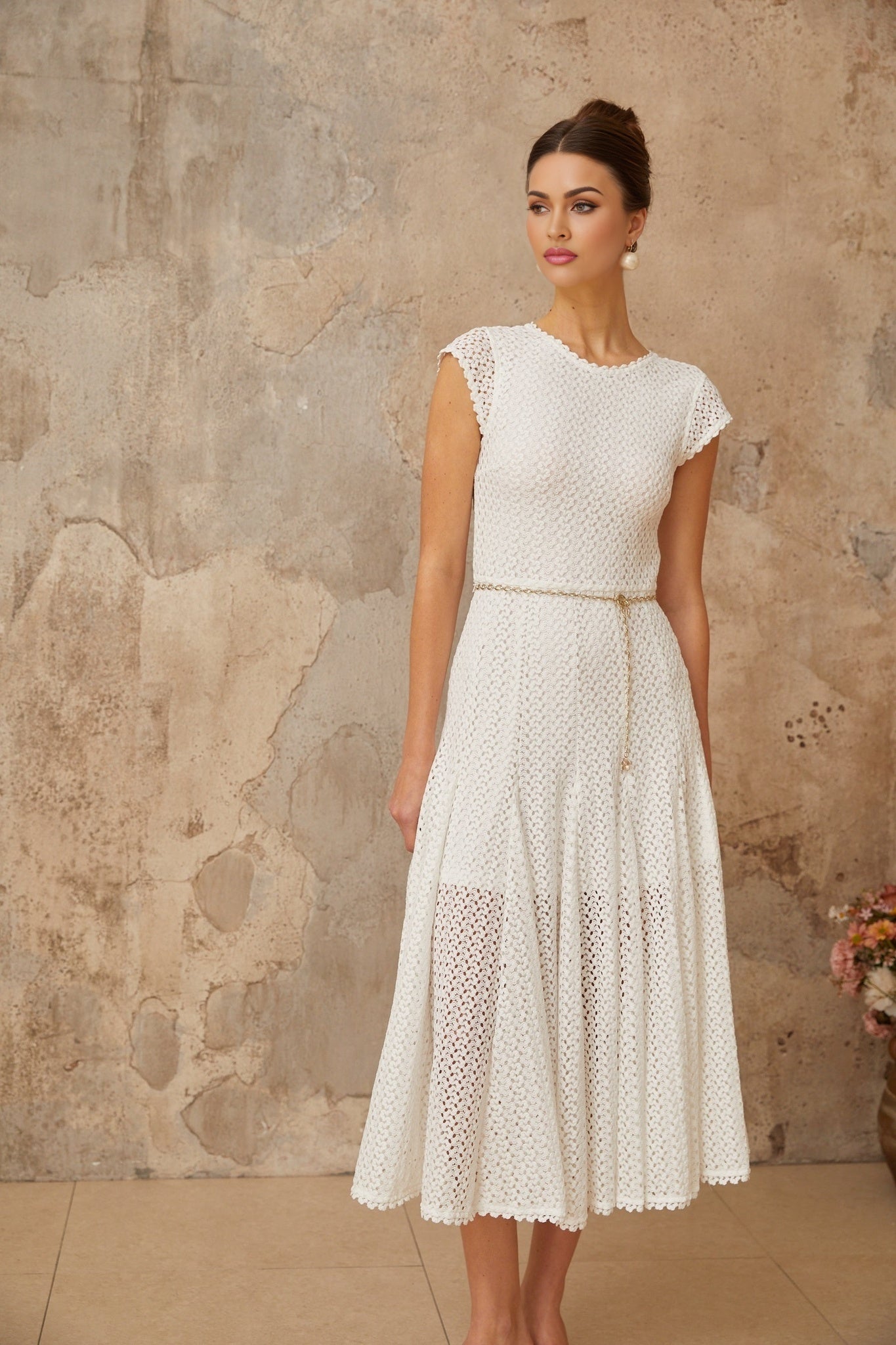 A white midi dress with shirred detailing and crochet knit pattern featuring a fitted bodice and flared skirt