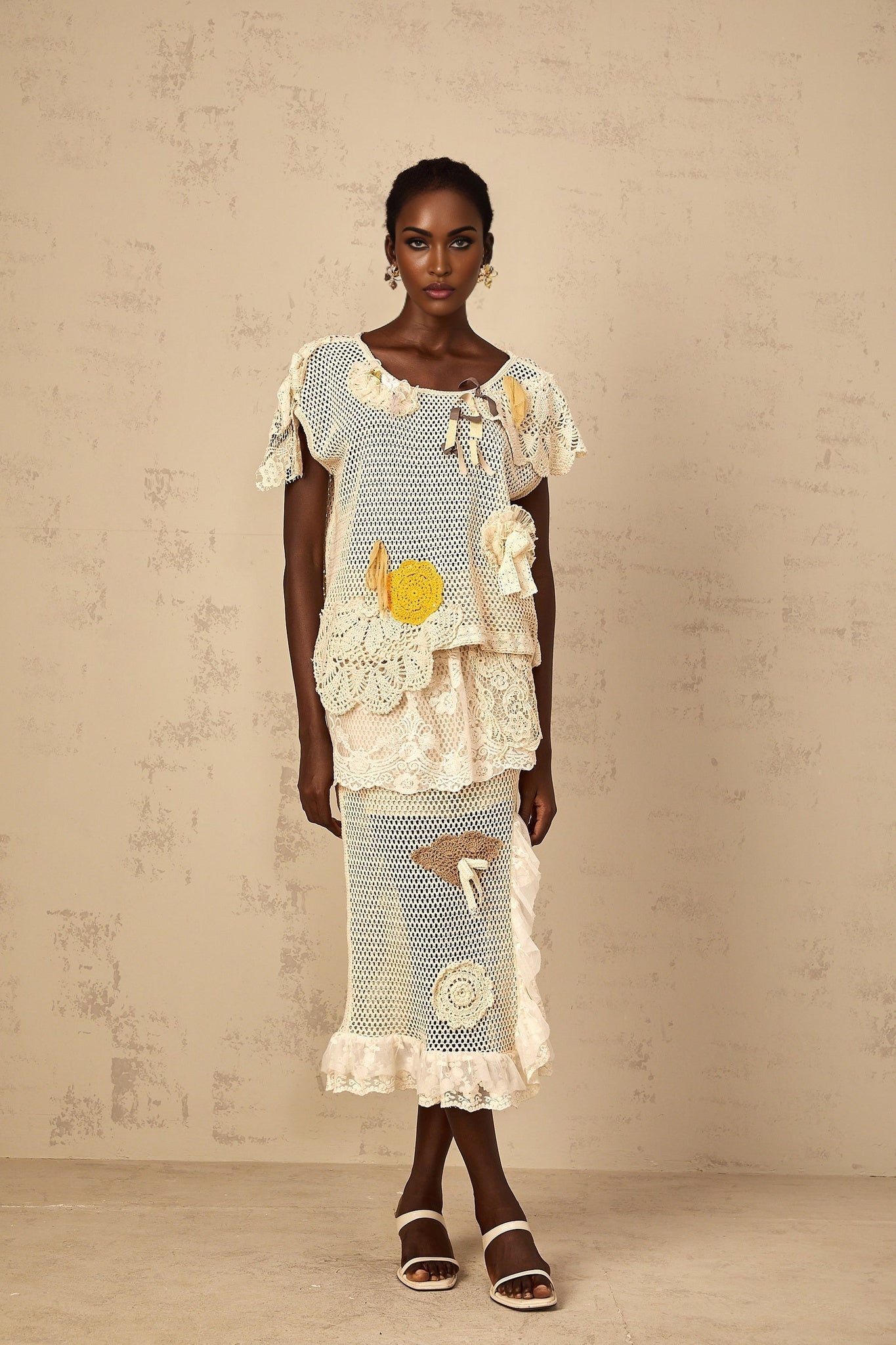 A white midi length skirt with a crochet knit pattern and lace panel details