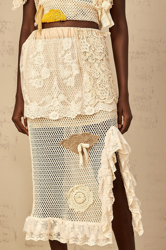A white midi length skirt with intricate lace panels and crochet knit detailing